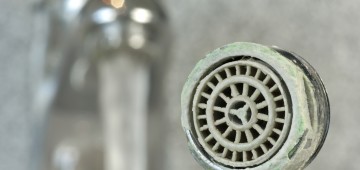 verkalkter Perlator vor Wasserhahn